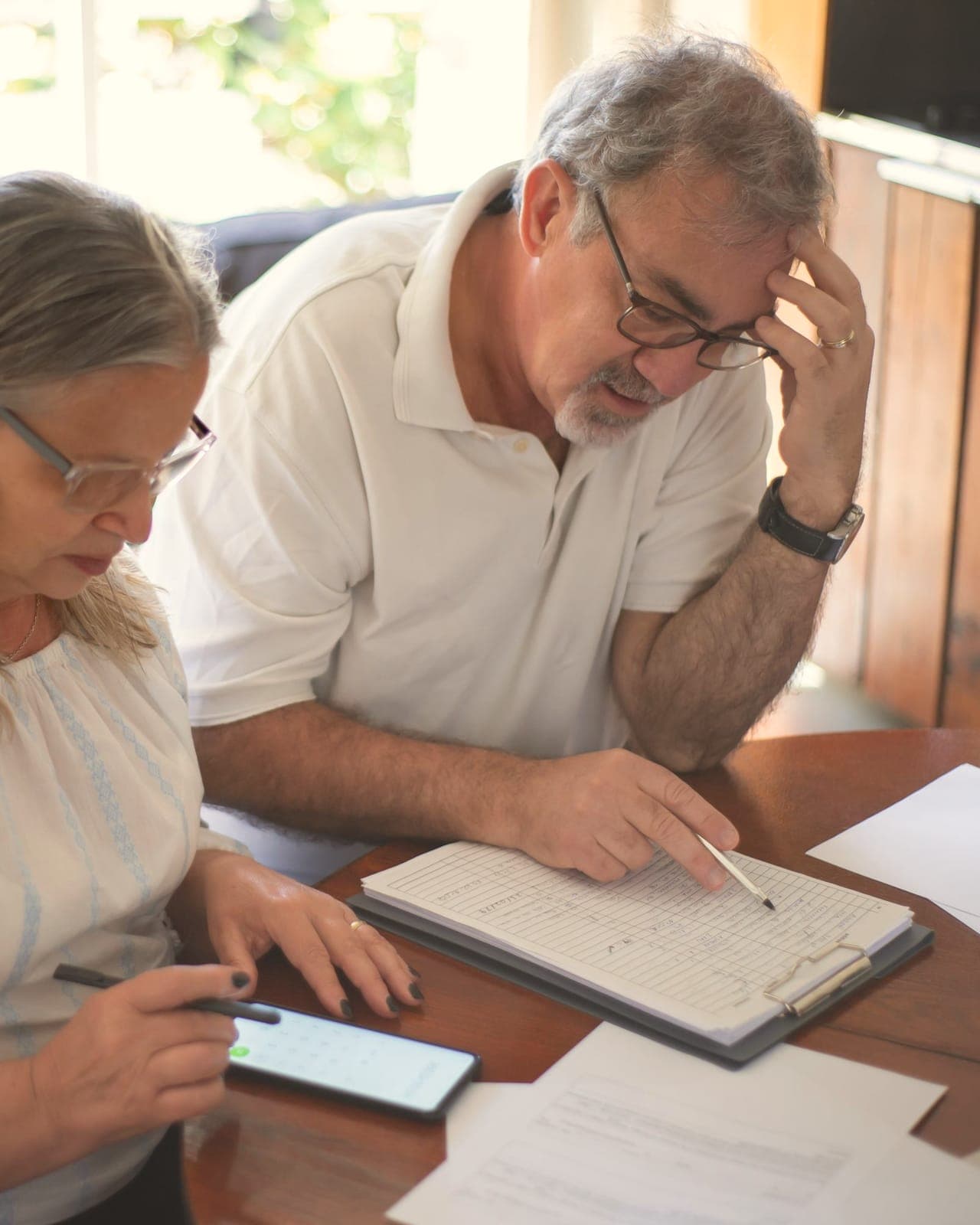 Un homme et une femme d'une soixantaine d'années, assis à une table, relisent ensemble des documents imprimés.