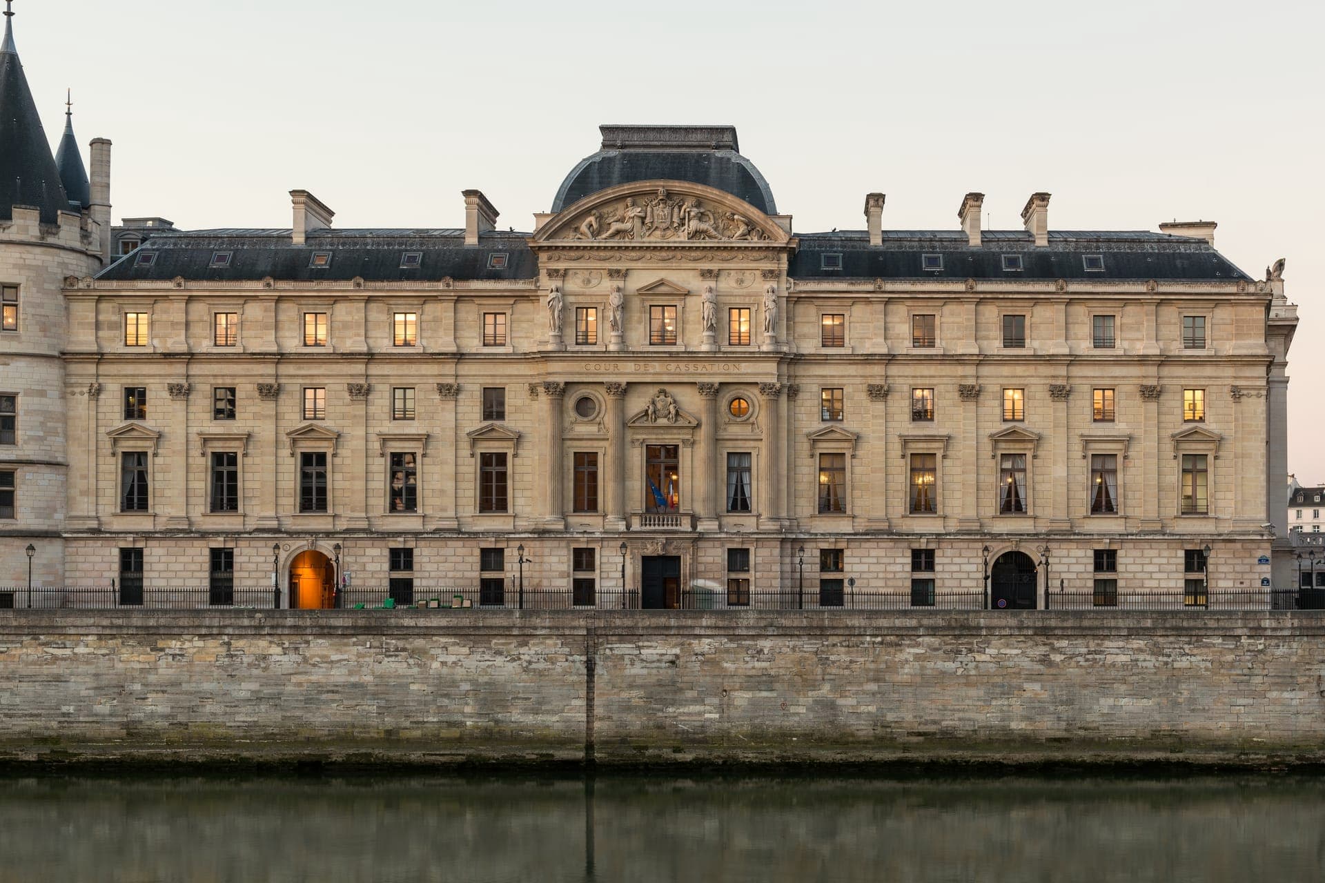 Façade classique en pierre claire d'un grand bâtiment à fronton sculpté et toit d'ardoise, au bord de la Seine, derrière un haut quai de pierre ; l'inscription « Cour de cassation » est gravée au centre.